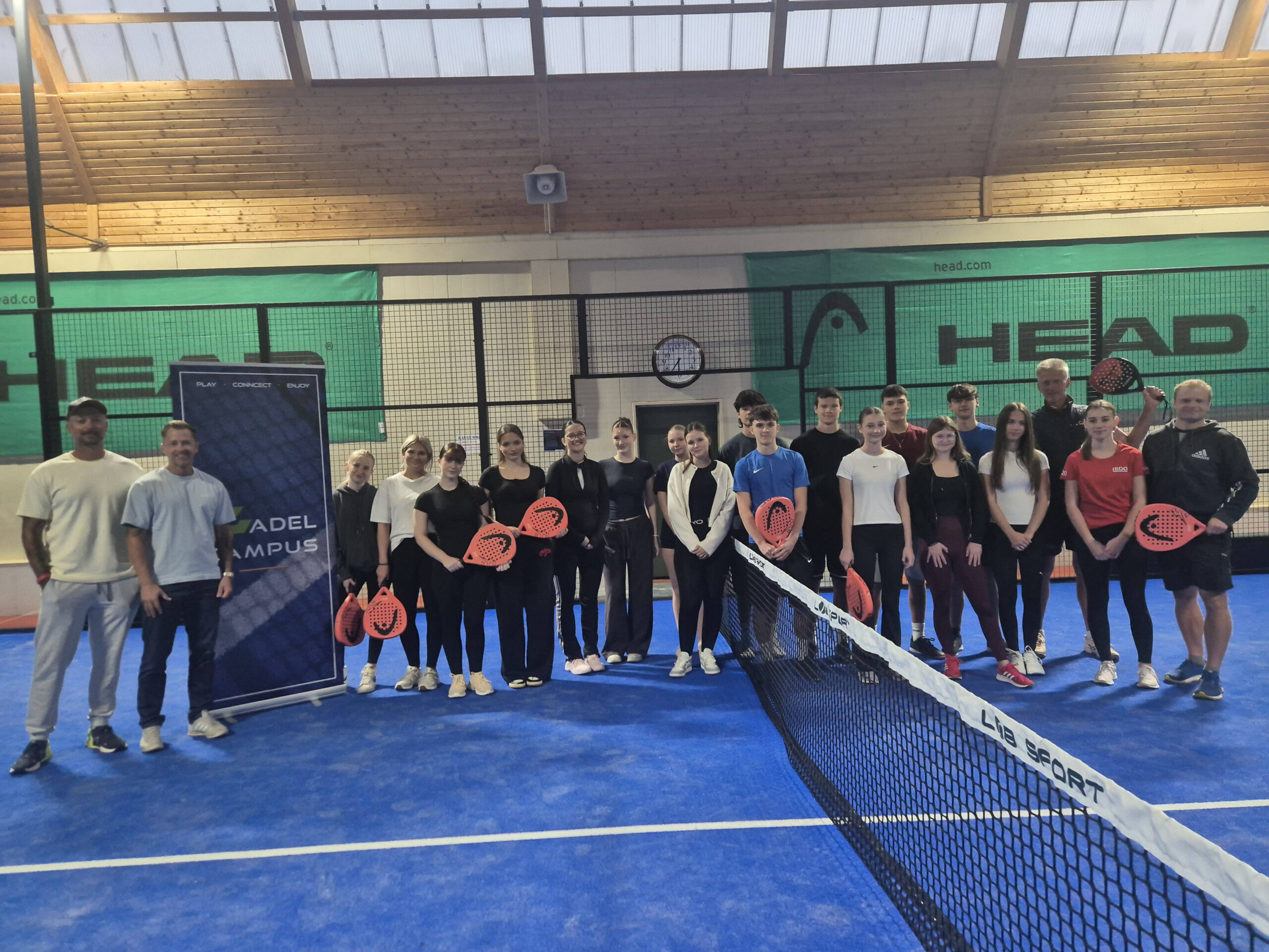 Padel-Spieler mit Schlägern stehen auf einem blauen Padel-Court in Österreich.